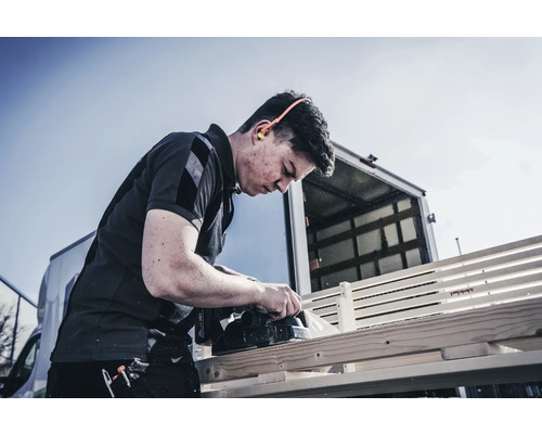 Handwerker hobelt Holz mit Elektrohobel im Aussenbereich
