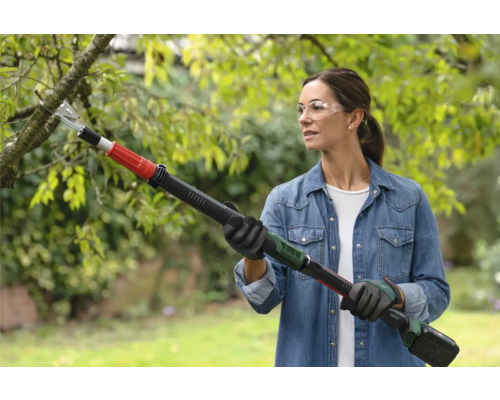 Frau benutzt Akku-Hochentaster zum Schneiden eines Astes