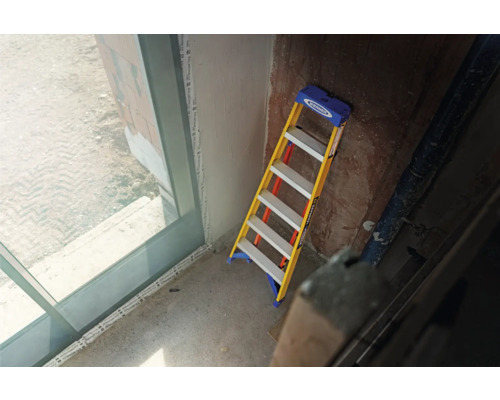 Eine Stehleiter im Innenraum, die an einer Wand lehnt.