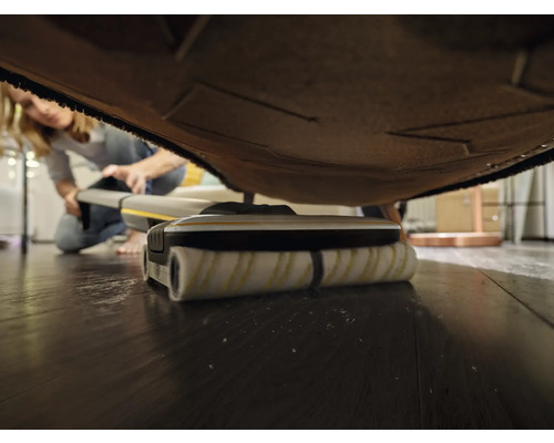 Bodenreinigungsgerät bei der Reinigung unter einem Möbelstück