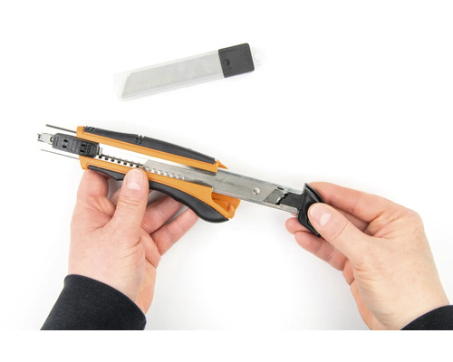 Hände die ein Cuttermesser halten mit Ersatzklingen