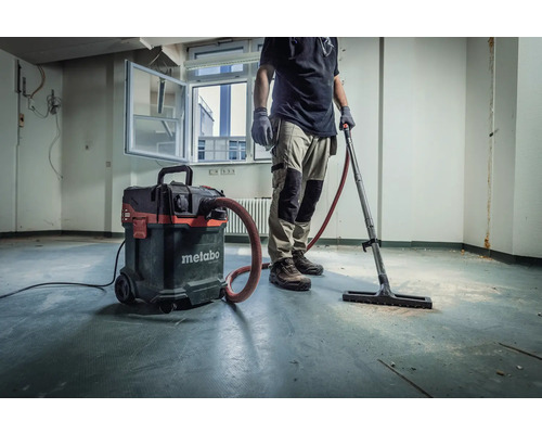 Handwerker mit Metabo Industriesauger zum Reinigen eines Raumes.