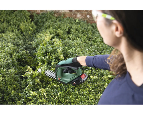 Frau schneidet Hecke mit Akku-Heckenschere