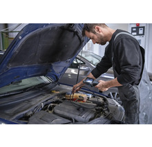 Ein Mechaniker inspiziert mit einer Inspektionskamera den Motorraum eines Autos.