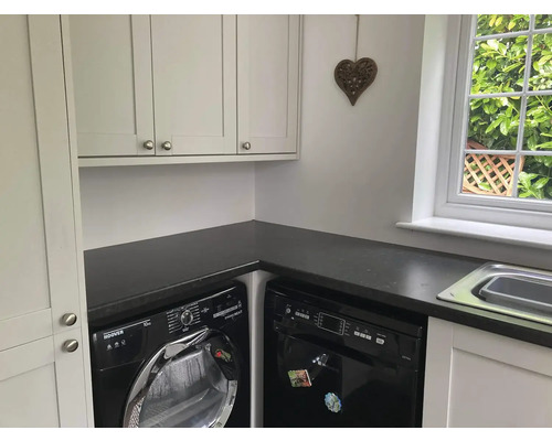 Waschküche mit Waschmaschine, Geschirrspüler, Spüle und weißen Schränken