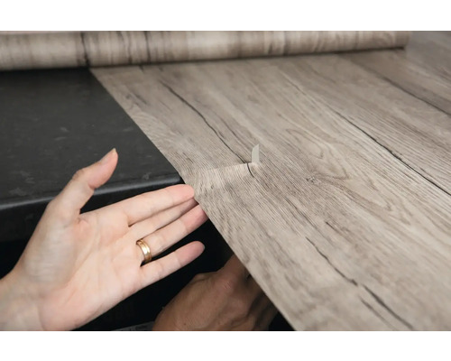 Selbstklebende Dekorfolie mit Holzoptik wird angebracht