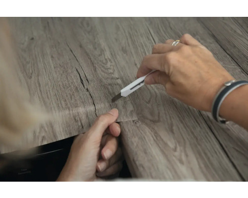 Zuschneiden von Vinylboden mit einem Cuttermesser.