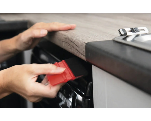 Eine Person verwendet einen Rakel zur Folienanbringung auf einer Oberfläche in einer Küche.