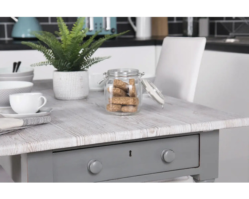 Dekoratives Arrangement mit Tisch, Geschirr und Vorratsglas in einer Küche.