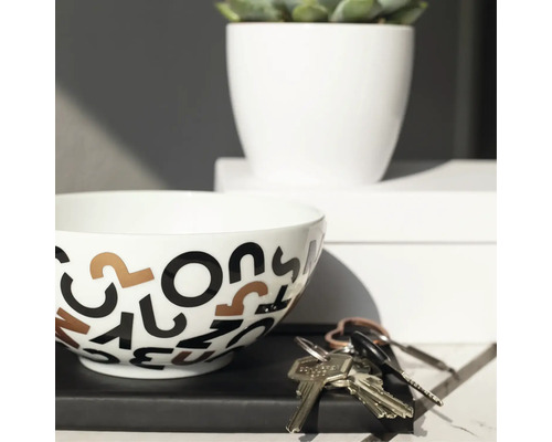 Dekorative Schale mit Buchstabenmuster, Topfpflanze und Schlüssel auf einem Tisch