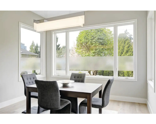 Esstisch mit Stühlen in einem hellen Raum mit Fenstern und Sichtschutzfolie