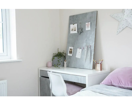 Schreibtisch mit Memoboard, Stuhl und Dekoration in einem hellen Raum.