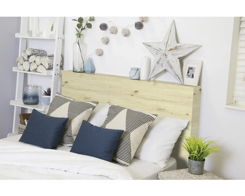 Schlafzimmer mit Holzkopfteil, Kissen und dekorativen Elementen für eine gemütliche Atmosphäre