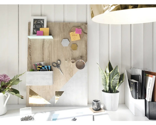 Dekoratives Memoboard mit Regalen, Ablagefach und geometrischen Mustern auf einem Schreibtisch mit Pflanze und Büroartikeln