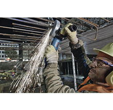 Ein Bauarbeiter verwendet einen Winkelschleifer zum Schneiden von Armierungseisen, wobei Funken fliegen.