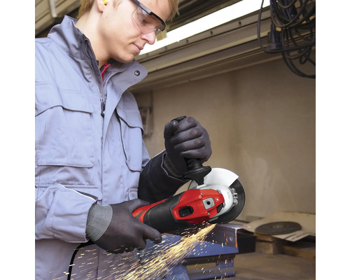 Mann mit Schutzbrille bearbeitet Metall mit einem Winkelschleifer und erzeugt Funken