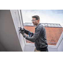 Mann verwendet eine Säbelsäge an einer Wand