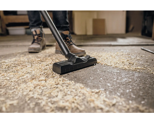 Eine Person saugt mit einem Staubsauger Späne auf.