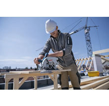 Handwerker sägt Holz mit einer Bosch Kreissäge auf einer Baustelle.