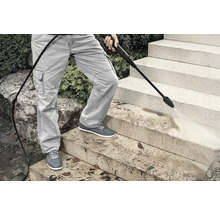 Eine Person reinigt Steintreppen mit einem Hochdruckreiniger.