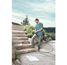Mann reinigt Steintreppe mit einem Hochdruckreiniger im Aussenbereich.