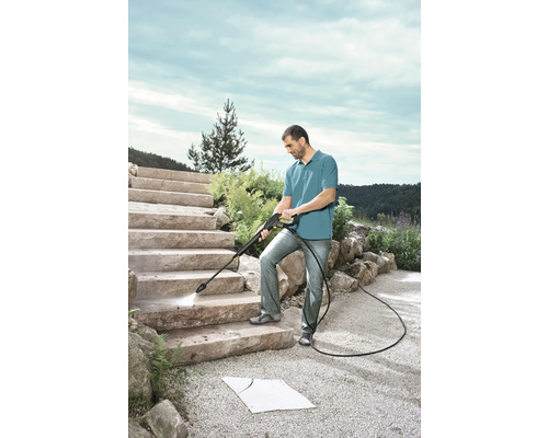 Mann reinigt Steintreppe mit einem Hochdruckreiniger im Aussenbereich.