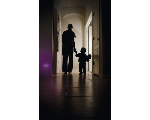 Silhouette einer Person, die mit einem Kind durch einen dunklen Flur geht