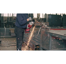 Ein Mann schneidet mit einem Winkelschleifer ein Metallstück ein.