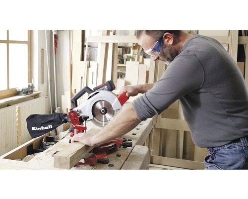 Ein Mann sägt ein Holzbrett mit einer Einhell Kapp- und Gehrungssäge.