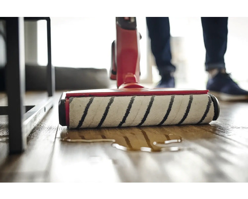 Aufsicht auf einen Waschsauger in Aktion auf einem Holzboden.