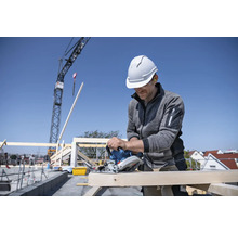 Handwerker sägt Holz mit einer Handkreissäge auf einer Baustelle.