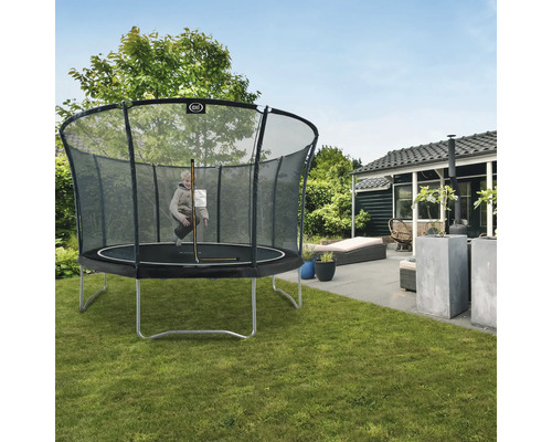 Kind springt auf einem Gartentrampolin mit Sicherheitsnetz.