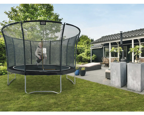 Kind springt auf einem Gartentrampolin mit Sicherheitsnetz