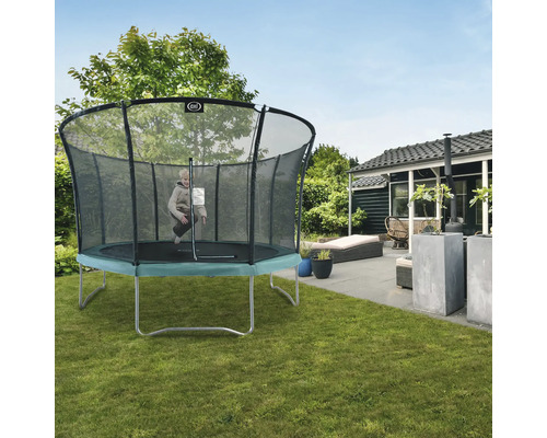 Ein Kind springt auf einem Trampolin mit Sicherheitsnetz in einem Garten.