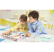 Zwei Kinder bemalen Textilien mit Textilmarkern an einem Tisch.
