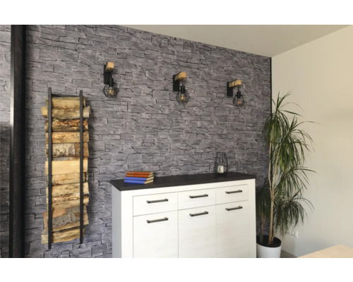 Wohnraum mit Holzlager, Kommode, Wandleuchten und dekorativer Wandverkleidung in Steinoptik