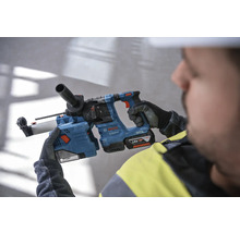Ein Arbeiter hält einen blauen Bohrhammer von Bosch mit einem 18 Volt Akku.