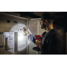 Ein Mann überprüft mit einer Einhell Lampe einen Sicherungskasten.