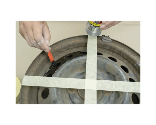 Eine Person trägt Rostschutz auf eine Autofelge auf