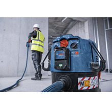 Industriestaubsauger mit Schlauch und Bauarbeiter im Hintergrund