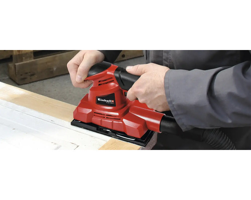 Ein Mann benutzt einen roten Einhell Schwingschleifer zum Schleifen eines Holzbretts.
