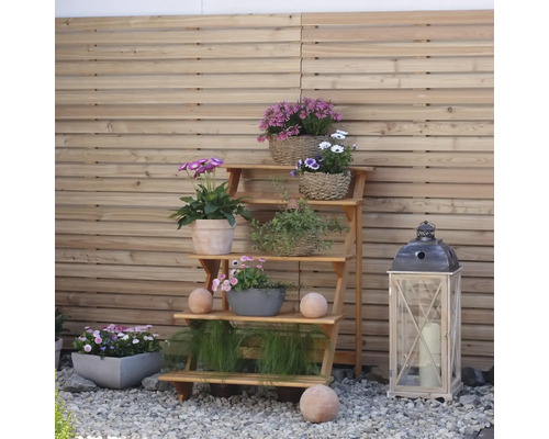 Blumenregal aus Holz mit verschiedenen Blumen und Dekorationen im Garten.