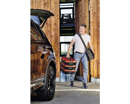 Mann trägt drei Werkzeugkoffer zum Auto