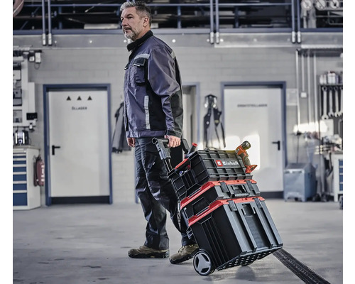 Mann transportiert Einhell Werkzeugkoffer auf Rädern in Werkstatt