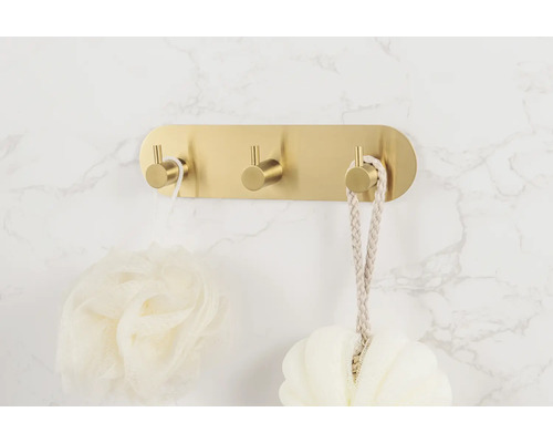 Goldener Wandhaken mit drei Haken und Bad-Accessoires.