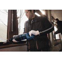 Ein Handwerker demontiert mit einer Säbelsäge ein Fenster.