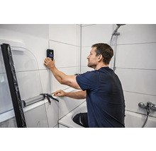 Mann benutzt Wandscanner im Badezimmer zur Badrenovierung.