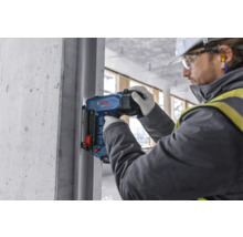 Ein Arbeiter verwendet einen Bolzensetzgerät auf einer Baustelle.