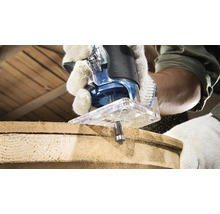 Person benutzt eine Oberfräse, um ein Holzstück zu bearbeiten