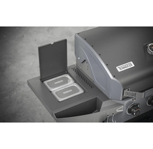 Detailansicht eines Gasgrills mit geöffnetem Warmhalterost und dem Tenneker Logo.